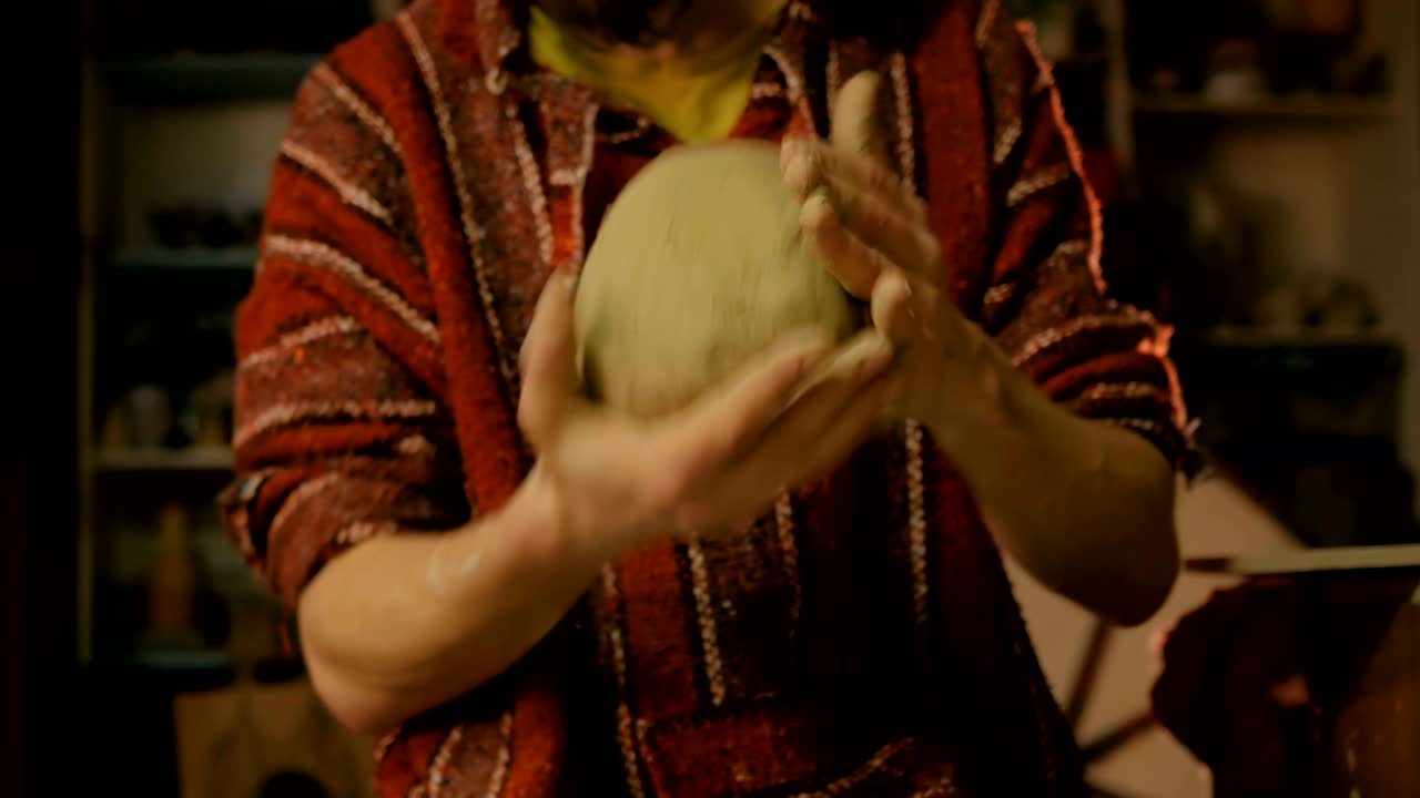 Professional male potter kneads clay in pottery workshop