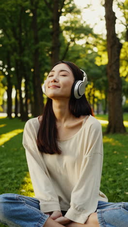 young woman enjoying music in a park with headphones