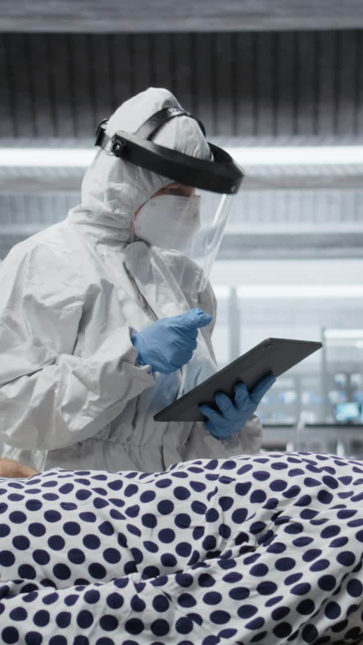Video verticale: un medico in tuta protettiva e guanti visita un paziente in quarantena