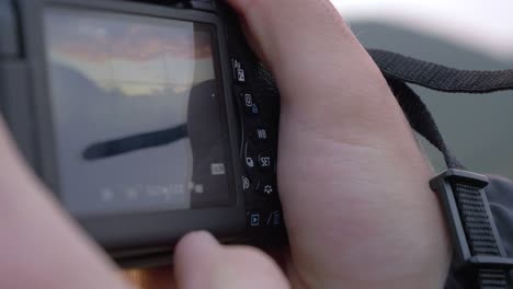 close-up of a young man taking a picture with a canon reflex camera in slowmotion in exterior with cloudy blue sky