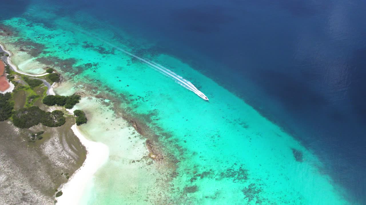 Veduta aerea dall'alto di una barca che naviga in acque limpide vicino a una barriera corallina a Cayo de Agua.