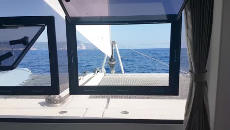 front view of catamaran zooming out through window inside the cabin