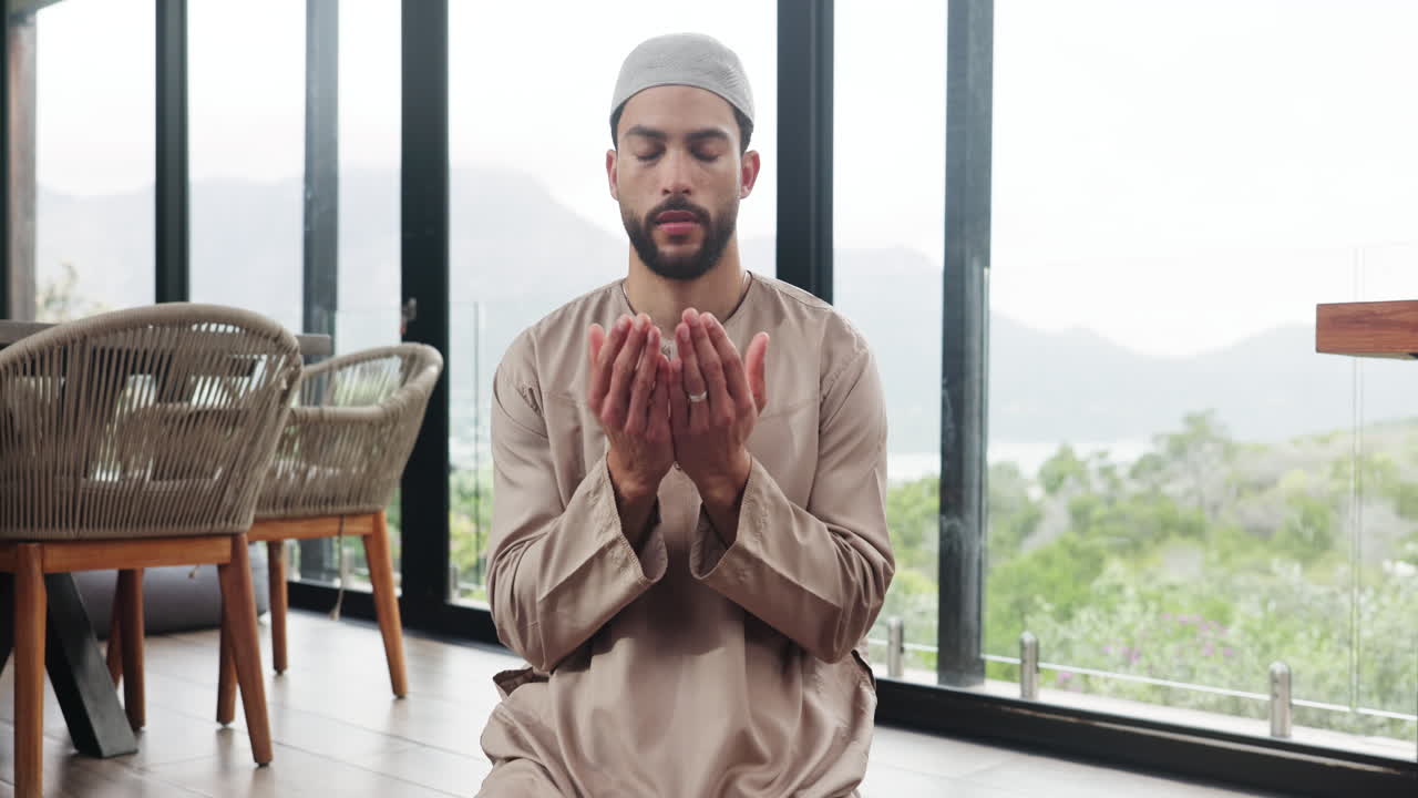 Pria Muslim berdoa dengan tangan menengadah di rumah modern.