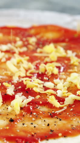 esparciendo aderezos de queso en la base de la pizza