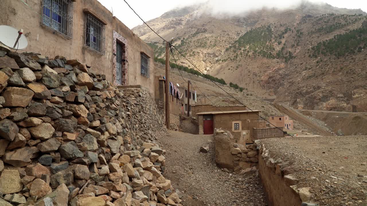 In the heart of the mountain village, stone houses with red-tiled roofs sit closely together, offering a picturesque view of the majestic Toubkal peaks in Morocco