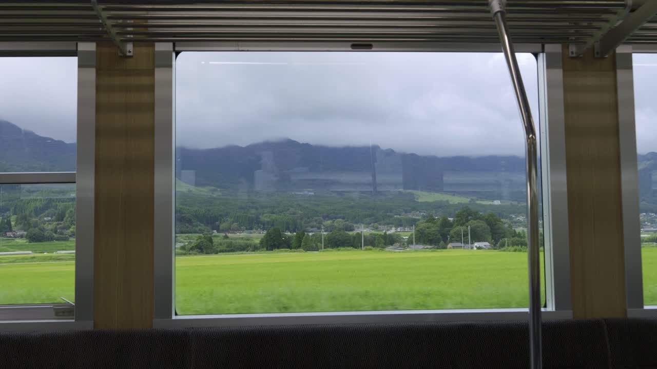 View from a Train Window: Green Fields and Distant Mountains