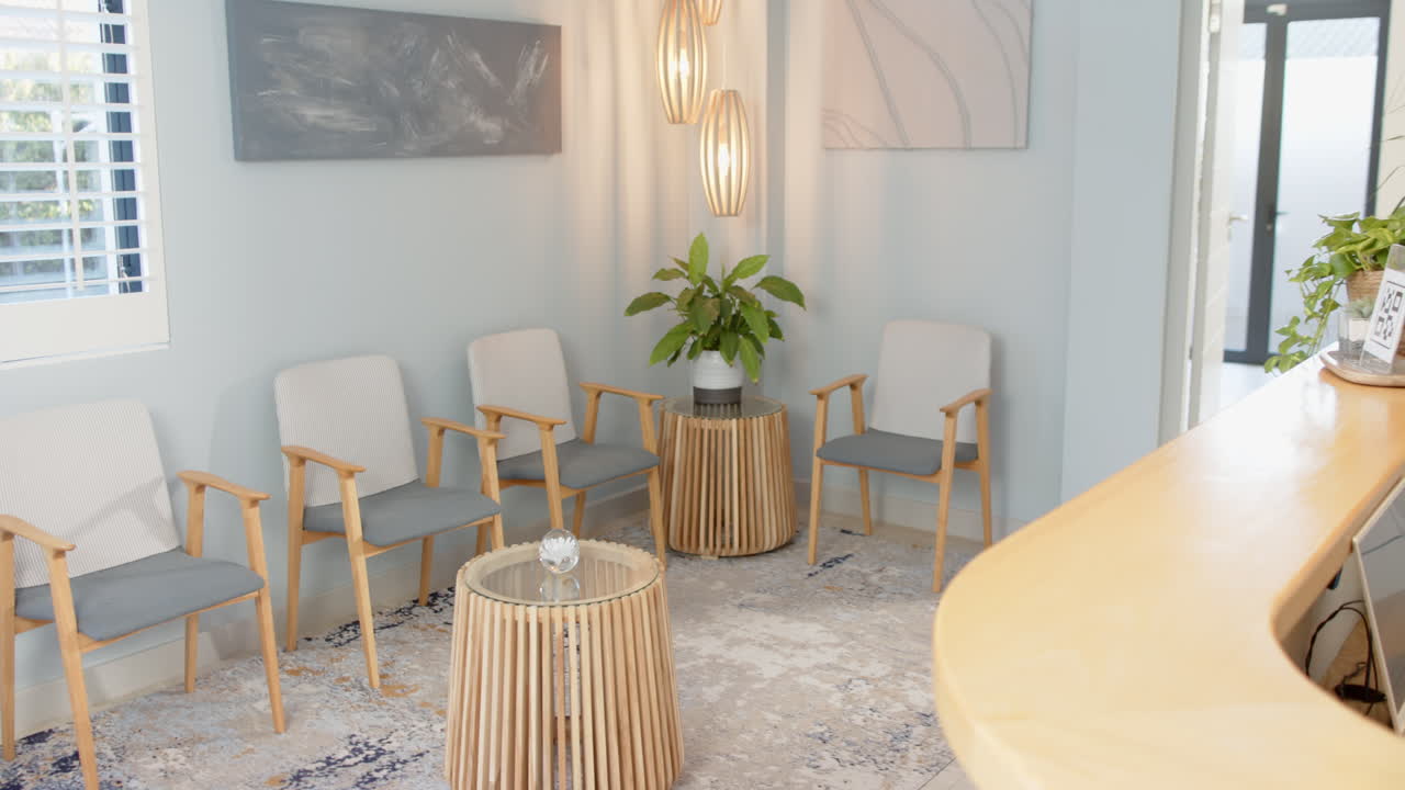 Waiting room with four chairs, round table, and two abstract paintings on wall