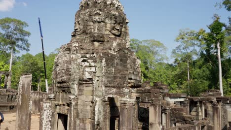 a breathtaking view of stone faces of angkor thom temple complex in cambodia, surrounded by lush greenery.