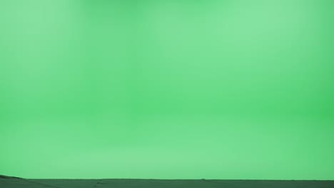 estudio de pantalla verde: joven con mochila y auriculares usando teléfono inteligente para navegar por internet y redes sociales, escuchando música o podcast caminando felizmente a través de la sala de llaves cromáticas