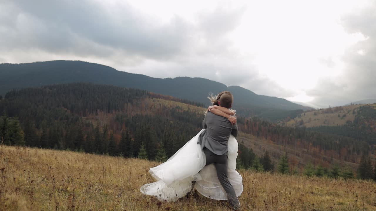 Dejlige nygifte brud og gom danser på en bjergskråning om efteråret i slow motion, bryllupspar familie