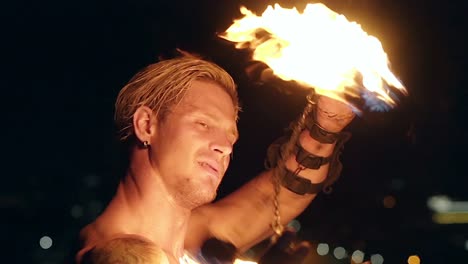 young blond male spins two burning pois around face slow motion shot close-up shot