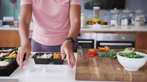 close up of woman wearing fitness clothing preparing batch of healthy meals at home in kitchen