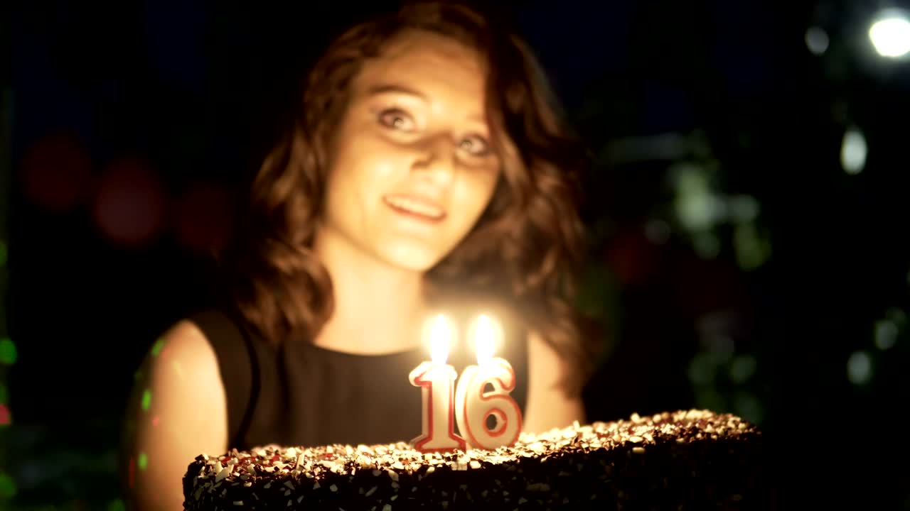 adolescente feliz en una fiesta de cumpleaños de 16 años con pastel y velas encendidas sonriendo y divirtiéndose, tiro de mano