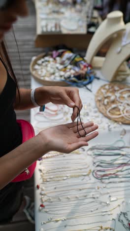 woman looking at beaded necklaces at a market