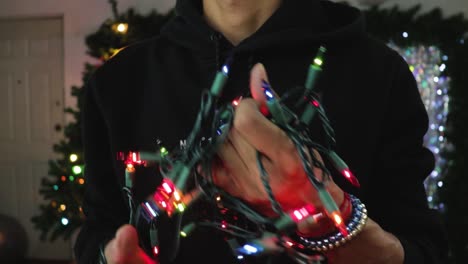 Man-trying-to-untangle-string-Christmas-lights-in-studio