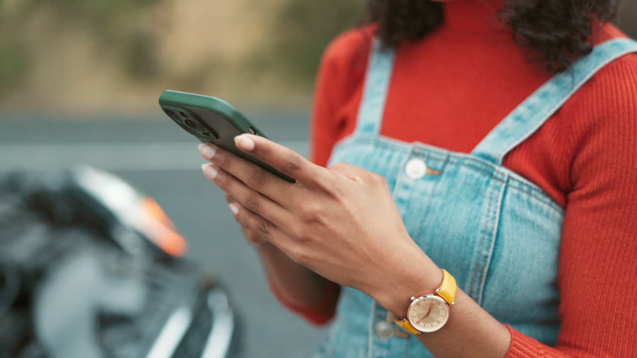Woman using mobile phone next to a broken down car