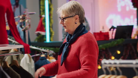 mujer anciana navegando por los estantes de blazer en la sección de hombres de la tienda de ropa, en busca del regalo perfecto de navidad para el marido durante la temporada de vacaciones de invierno. cliente buscando ropa para dar como regalos