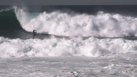 a massive mass of white foamy waves washes over and knocks the surfer off his board