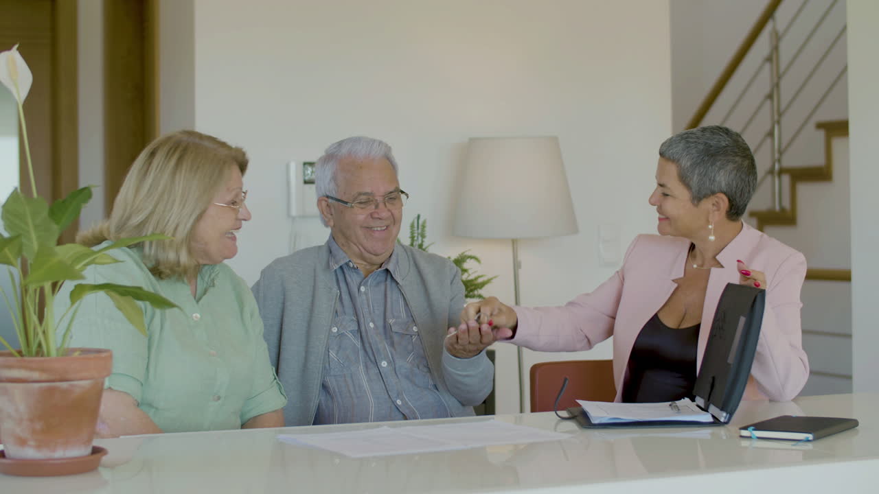 Realtor giving keys from new house to happy senior couple
