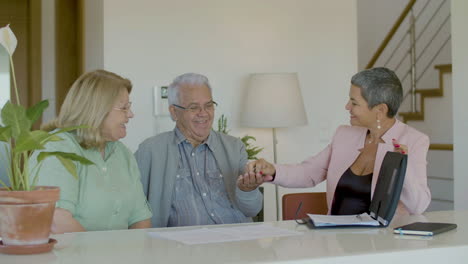 agente inmobiliario dando llaves de casa nueva a feliz pareja senior