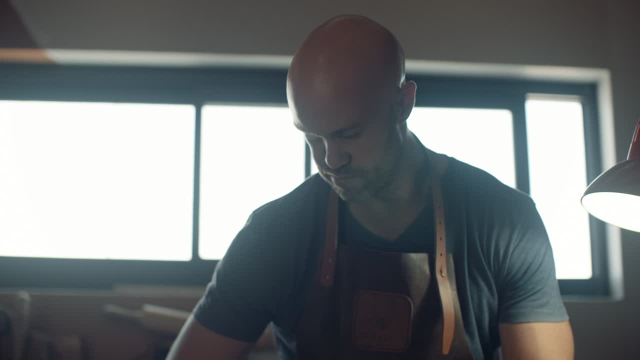 Upper half of artisan wearing handmade leather apron working in his workshop