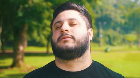 handsome beard man close up shot with eyes closed at the park in slow motion