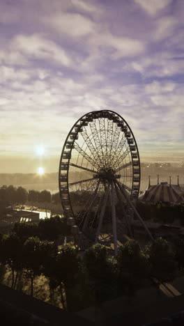 ferris wheel stands tall near water as sunset casts a warm glow
