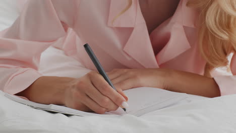 woman writing in a notebook in bed