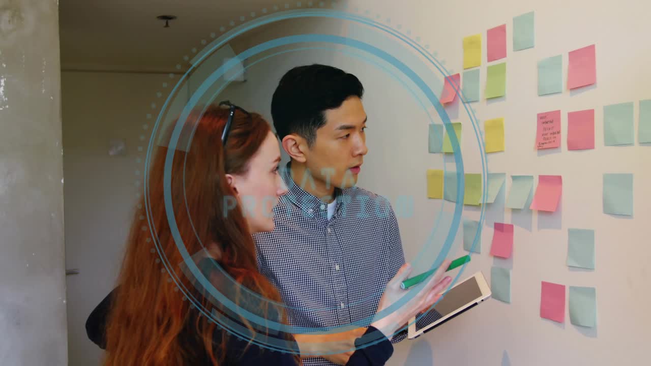 Woman tapping tablet and man pointing at post-it wall, HUD DATA PROTECTION growing sorting tasks