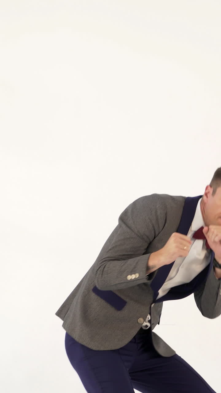 a man in a suit skillfully is copying the movements of a boxer during a fight in the studio. Parody from actor Vertical video