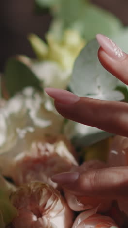 woman hand strokes fresh bouquet with rose flowers in room closeup slow motion. bridal ceremony ornate preparation. floral decor for wedding
