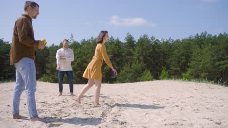 Side-view-of-a-group-of-caucasian-friends-playing-petanque-on-the-beach-on-a-sunny-day