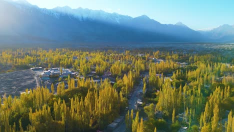 capturing the stunning aerial view of skardu valley with vibrant autumn foliage, town structures, and majestic mountains under golden sunlight