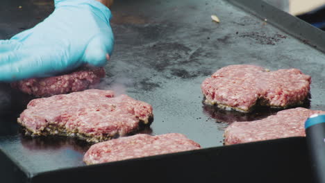 locked off close up shot of person cooking fresh ground hamburgers on a hot plate at a festival