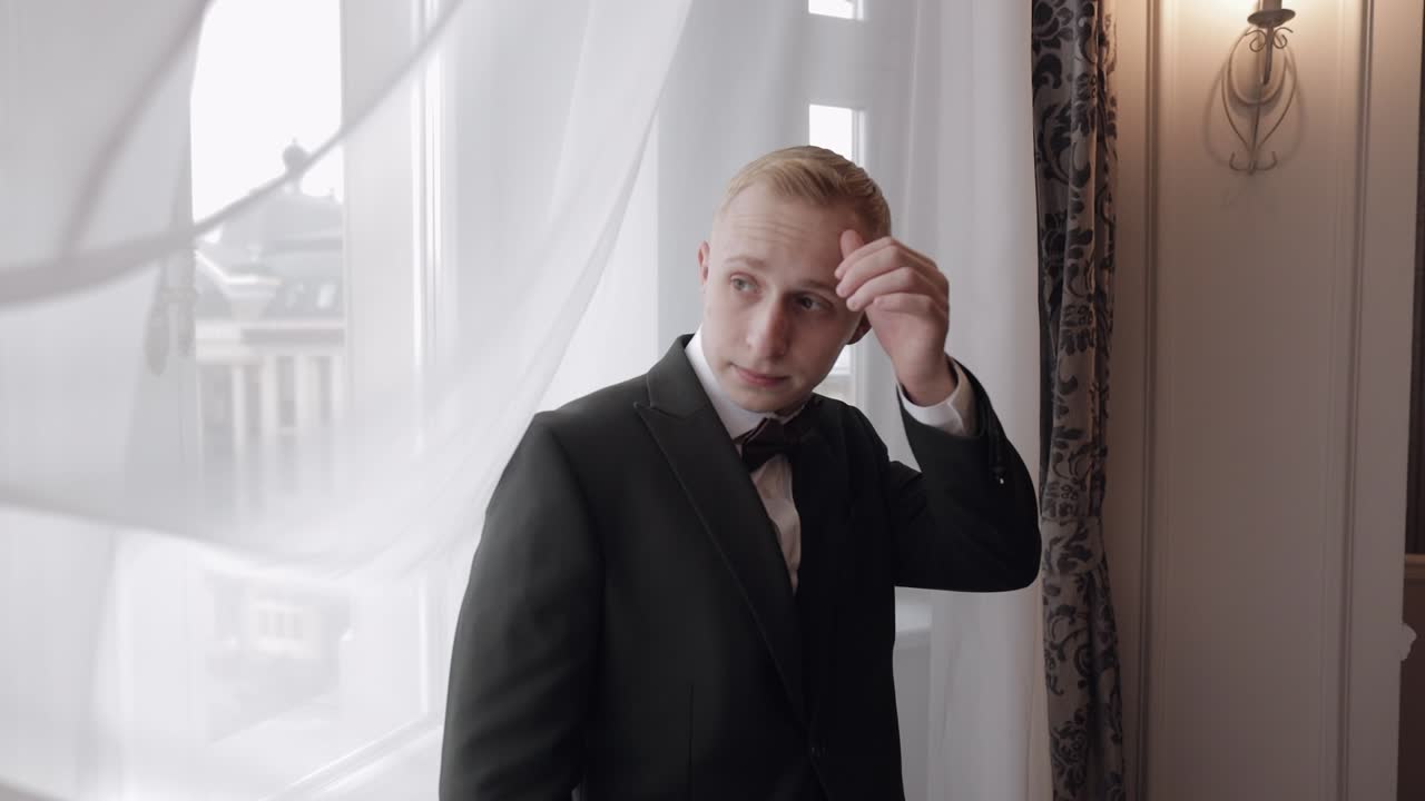 예쁜 세련된 신랑이 초록색 재 ⁇ 을 입고 거실에서 집에, 느린 동작 실내 초상화