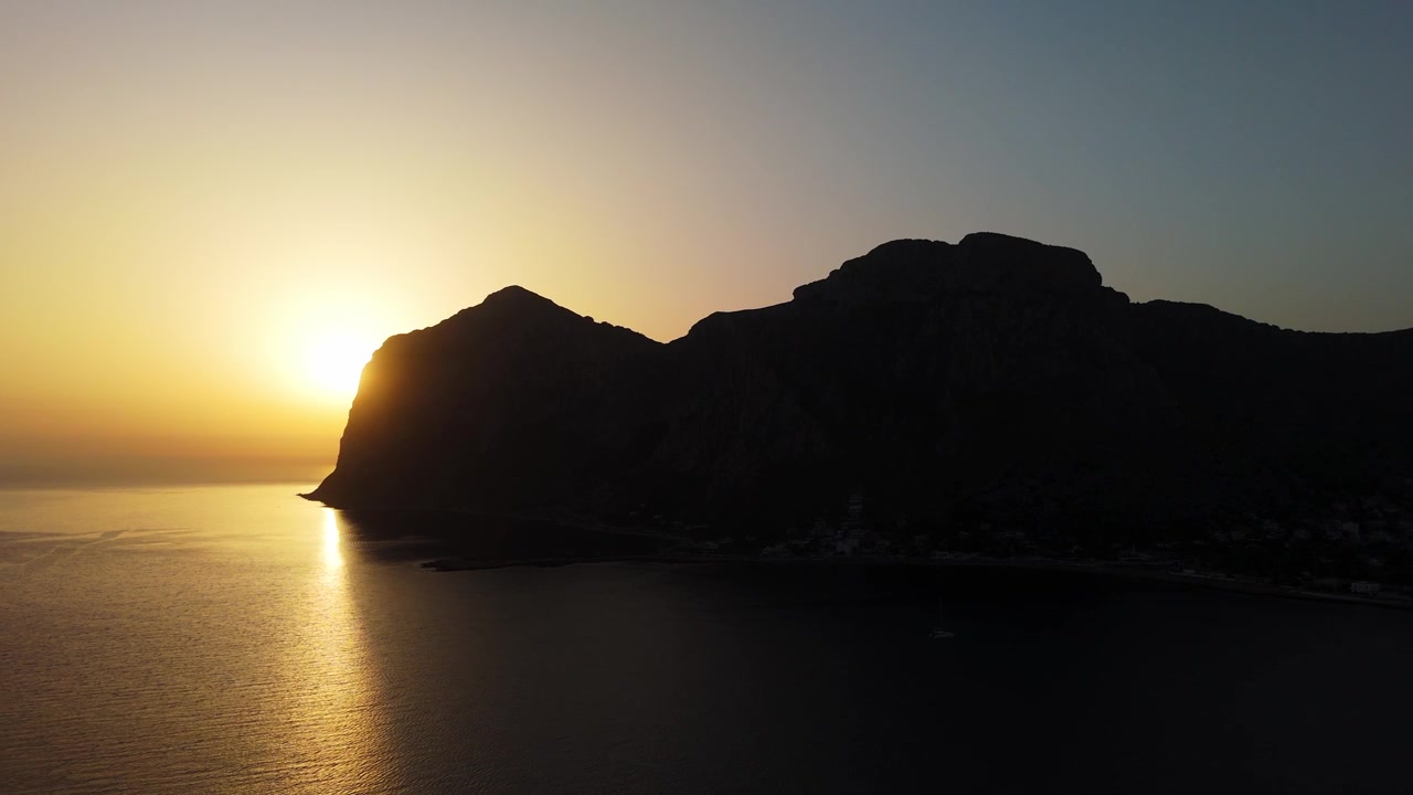 Silhueta dramática do nascer do sol do promontório de Capo Gallo em Palermo, Sicília. Vista aérea mostrando o promontório montanhoso escuro contra o céu do amanhecer.