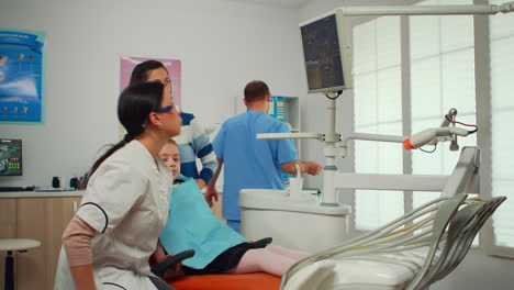 Stomatologist-pointing-on-digital-screen-explaining-x-ray-to-mother