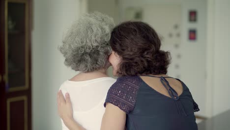 Daughter-and-mother-talking-on-sofa,-they-hugging-and-kissing