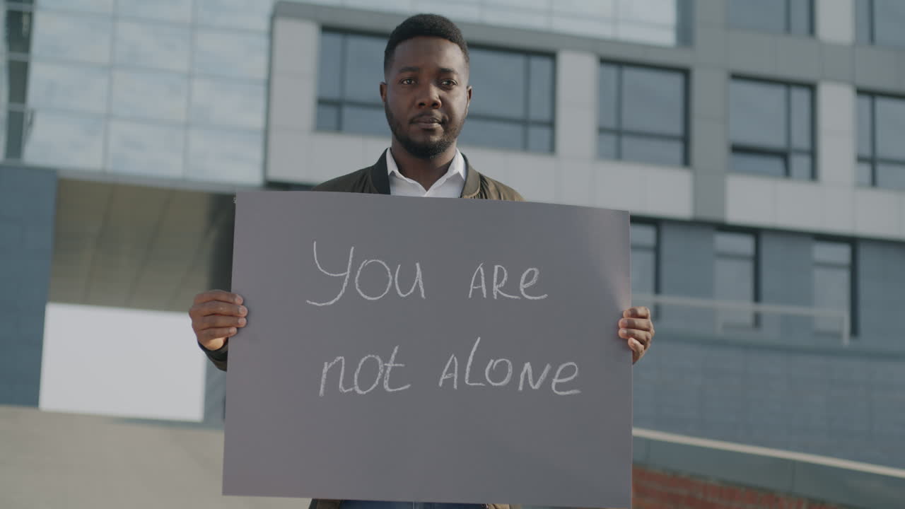 Man Holding a Sign Saying 'You Are Not Alone'