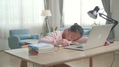 tired asia girl sleep on the table at living room after doing home work