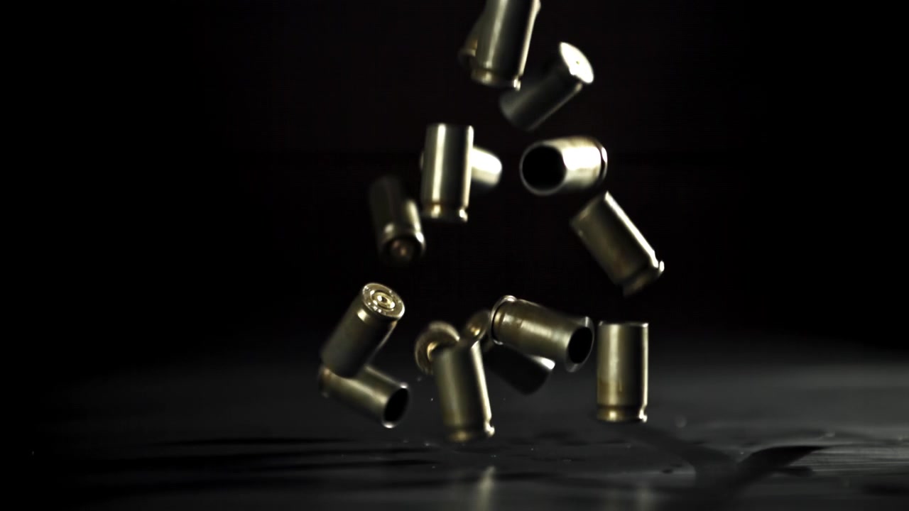 Bullet Casings Falling and Bouncing on a Dark Surface in Slow Motion