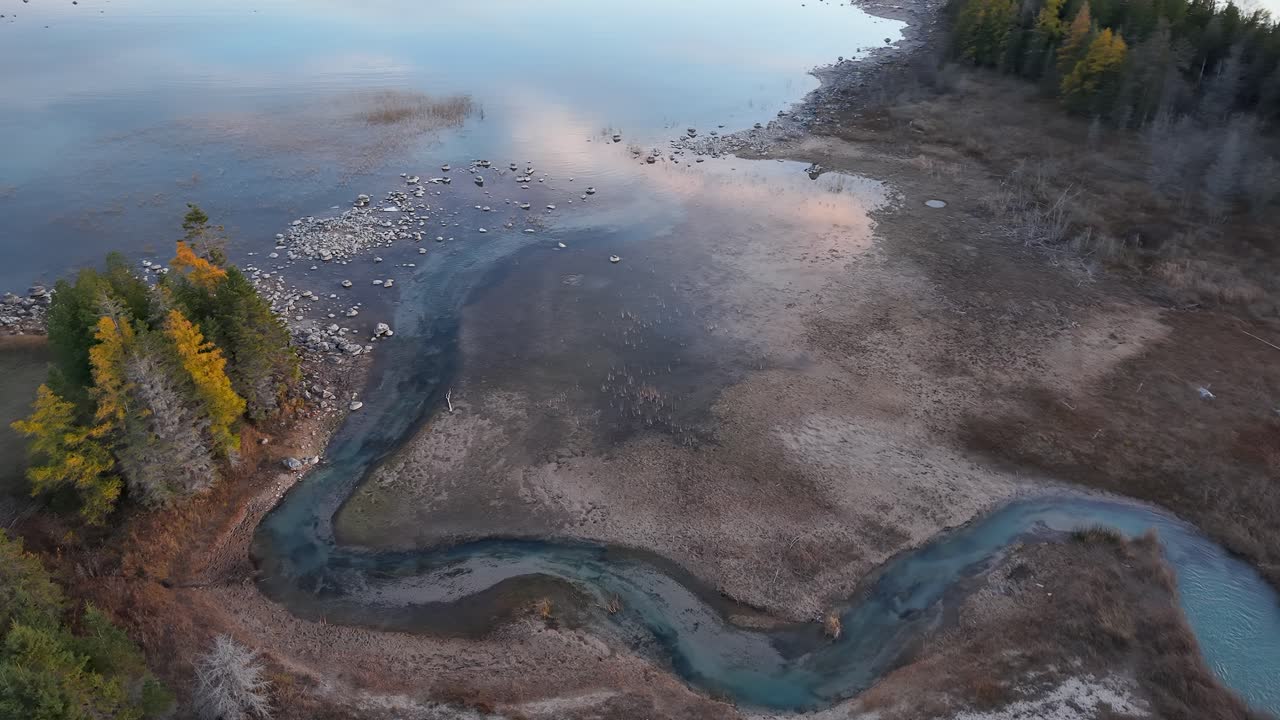 Aerial view of winding river through autumn forest and exposed sediment