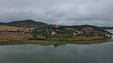 Vista-Aérea-De-Un-Día-Nublado-Del-Pueblo-De-Nanclares-De-Gamboa-Junto-A-Un-Lago-Tranquilo,-País-Vasco,-España,-Escena-Tranquila