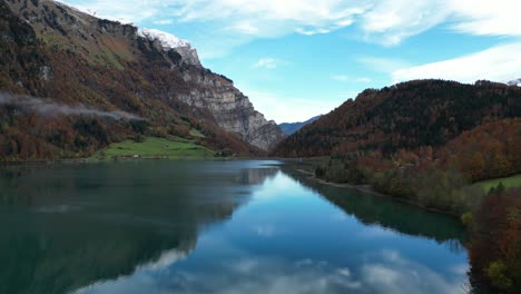 Langsames-Heranzoomen-Des-Sees-Im-Tal-Zwischen-Den-Hügeln-Während-Des-Tages-Mit-Blauem-Himmel-Und-Wolken-Im-Hintergrund