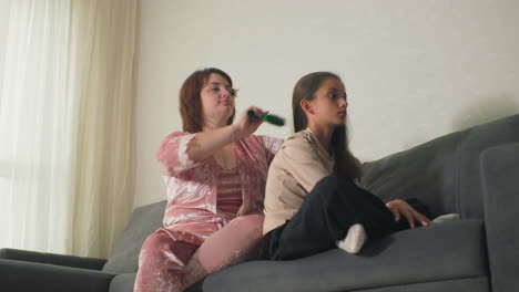 mother brushing daughter’s hair while sitting on couch at home. intimate, relaxing moment between parent and child. soft light from window adds warmth to cozy, peaceful atmosphere in living room
