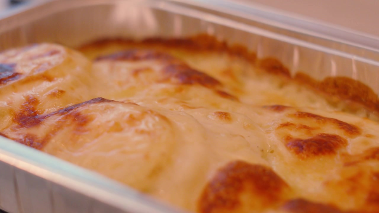 Gratin dauphinois fraîchement préparé, prêt à être servi. Idéal pour les documentaires culinaires, les marques alimentaires de luxe ou les promotions de restaurants. 4K.