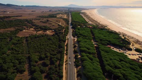 Wide-drone-shot-of-the-E-5-highway-cutting-through-Spain's-countryside-with-the-ocean-off-to-the-right