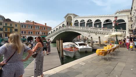 wide view of rialto bridge in venice italy, tourists with masks on during pandemic visiting bridge. dolly shot.