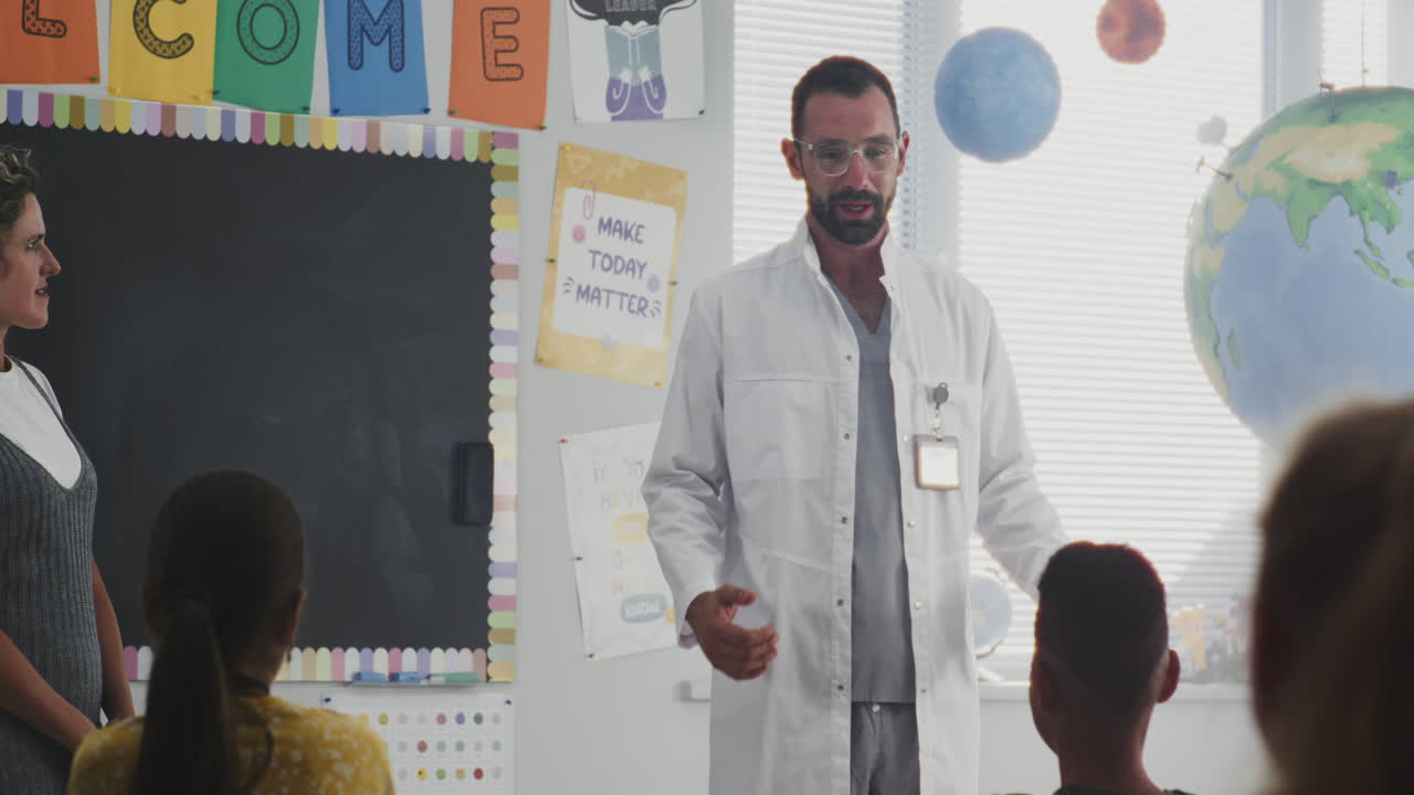 Female Doctor Visiting Classroom Giving Lecture to Curious Primary School Students About Health and