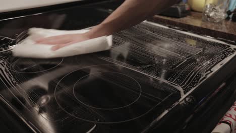 wiping off the soapsuds on the top of electric induction convection range with a clean dry cloth - close up shot